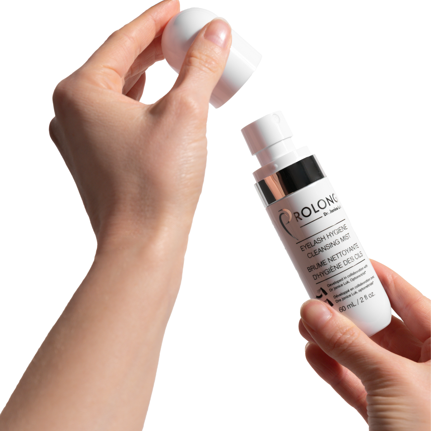 A close-up of a person's hands holding a white bottle of Prolong Lash Eyelash Hygiene Cleansing Mist and lifting its cap against a solid white background.