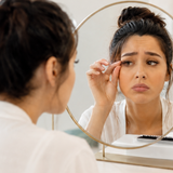 Woman checking thinning lash extensions in mirror.