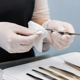 Lash artist cleaning tweezers between client application