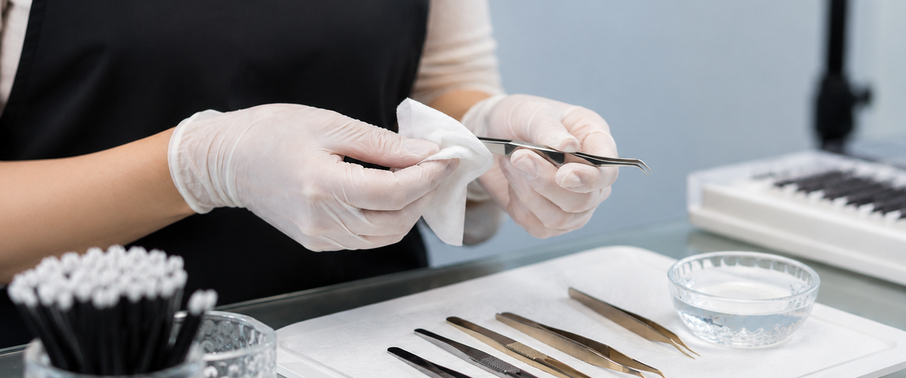 Lash artist cleaning tweezers between client application