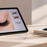 Tablet displaying a digital lash mapping app beside extension trays and tweezers on a salon counter.