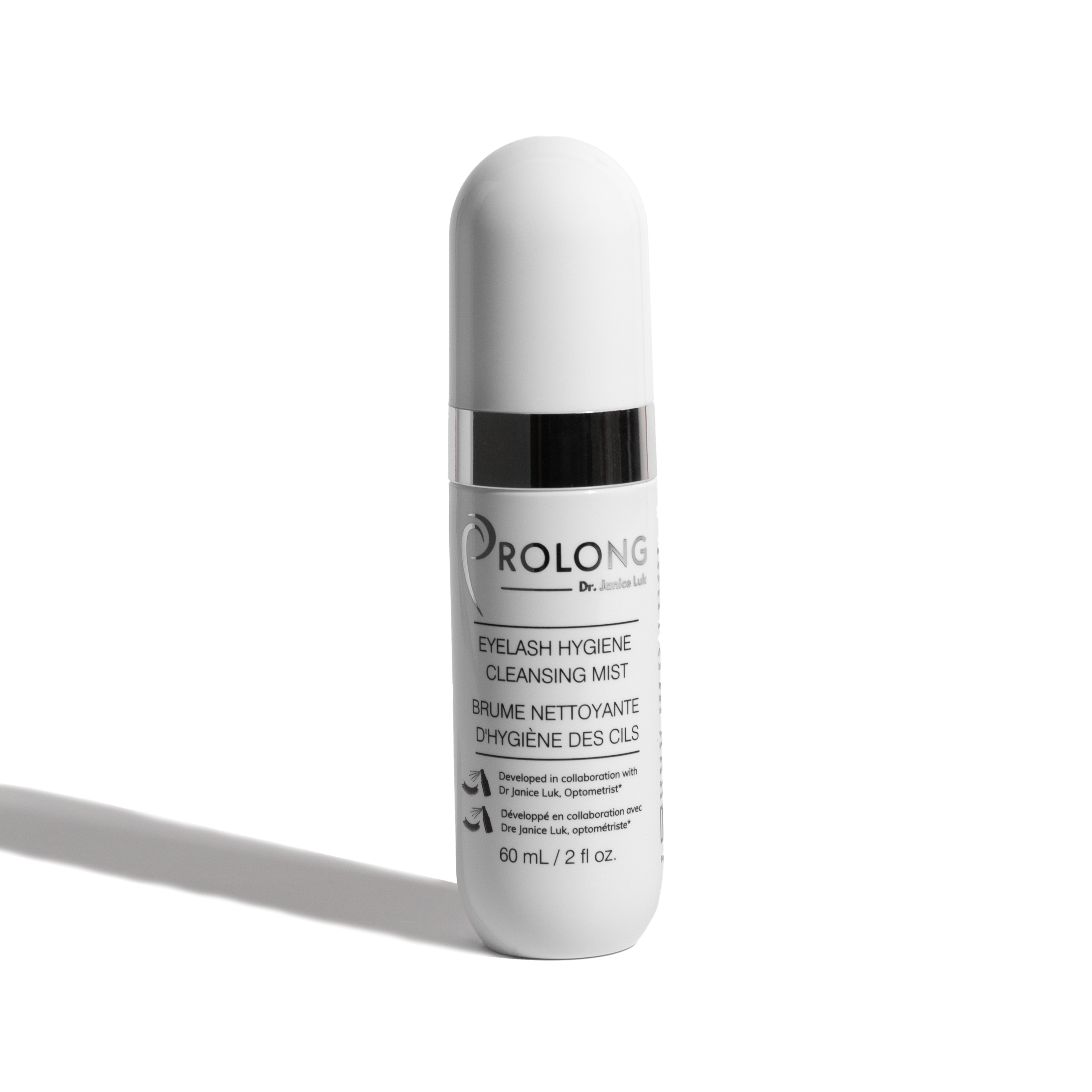 A white cylindrical cosmetic bottle with a ribbed cap and a black collar, labeled 'PROLONG CR JANICE LUK EYELASH HYGIENE CLEANSING MIST' on a clean white background with a soft shadow.